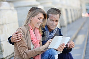 Couple of tourists sightseeing town with tablet