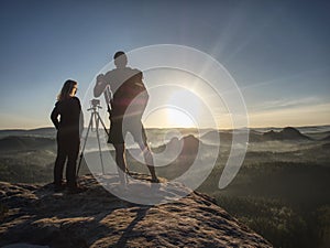 Couple tourists take pictures to background of hills and sky