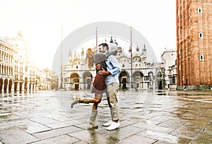Couple of tourists visiting Venice, Italy - Boyfriend and girlfriend dancing under the rain on city street at sunset