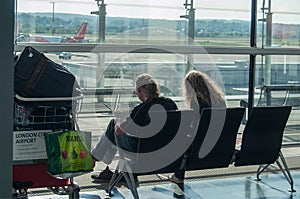 Couple of tourists waiting in boarding hall with a suitcase at the airport