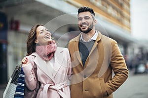 Couple of tourists walking in a city street and shopping together.