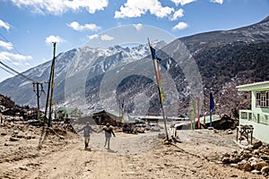 Couple tourists walking on the yellow stone ground to black mountain with snow on the top at Thangu and Chopta valley in winter.