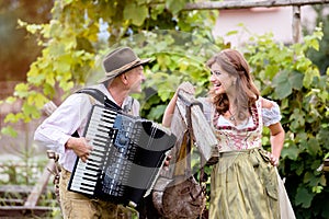 Couple in traditional bavarian clothes with accordion, green gar