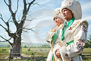 Couple in traditional dress, on background epic ancient tree at the middle of rural landscape.