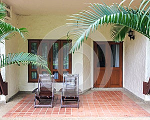 Couple of Traditional Wooden Deck Chairs on Patio of Balcony or Terrace in Open Area in front of Windows and Doors for Relax