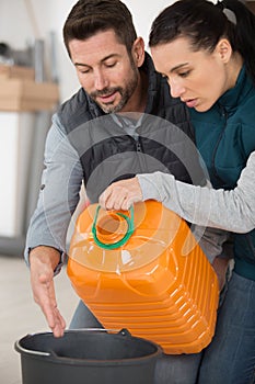 Couple transfering liquid from plastic container