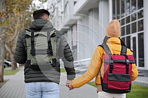 Couple with travel backpacks on city street, back view. Urban trip