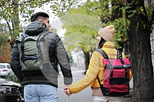 Couple with travel backpacks on city street, back view. Urban trip