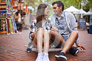 Couple, travel on skateboard and happy in city, outdoor and conversation with partner, learn together and relationship