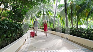 Couple traveler man and woman girl in red dress with suitcase at luxury resort