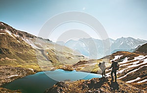 Couple travelers holding hands on mountain cliff over lake together