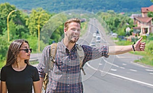 Couple travelers man and girl hitchhiking at edge road nature background. Travel by autostop. Couple hitchhikers
