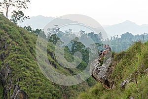 Couple travelers Man and Woman sitting on cliff, relaxing. Mountains aerial view