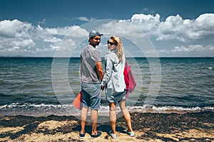 Couple Travelers Man And Woman Standing On Seashore And Looks At The Camera Adventure Travel Journey Concept
