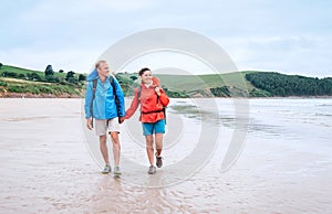 Couple travelers walk on the coast of Biskay Bay in North Spain, part of camino del Norte famous piligrims route