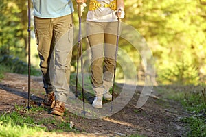 Couple with trekking poles hiking in forest, closeup