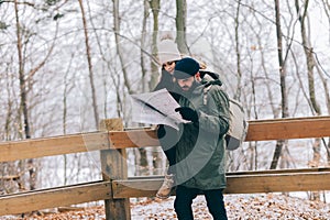 Couple trekking in winter in the forest looking at map.