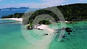 Couple at a tropical beach in Thailand with black stones in the ocean of Koh Kham near Koh Mak