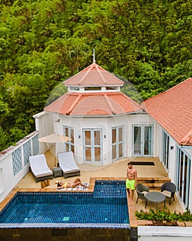 couple in tropical pool villa during vacation, drone view at pool bungalow in rainforest