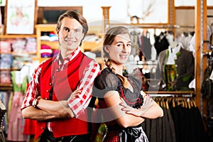 Couple is trying Dirndl or Lederhosen in a shop