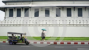 A couple and tuk tuk was passing a Grand Royal Palace area, Bangkok Thailand