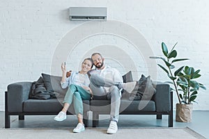 couple turning on air conditioner during the summer heat at home