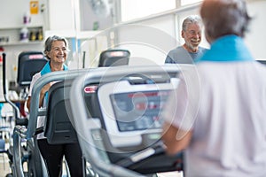 Couple of two happy and fitess seniors doing exercise in the gym together running on the tapis roulant - active lifestyle