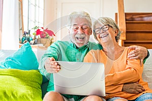 Couple of two happy mature and old people or seniors at home sitting on the sofa enjoying and having fun laughing together looking