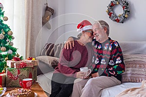 Couple of two happy seniors and mature people sitting in the sofa having fun together wrapping the gifts and presents - pensioners