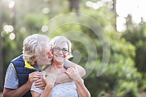 Couple of two old people together hugged at the wood or forest - love concept and defocused background - married seniors enjoying