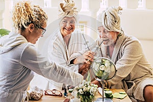 Couple of two seniors enjoying a spa and massage traetment together with an assistance helping them - drinking cocktails and