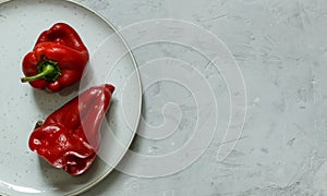 A couple of ugly red peppers on a plate. Horizontal orientation with space, top photo