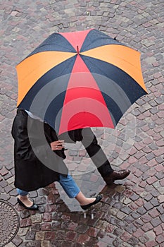 couple with umbrella on cobbles place in the city