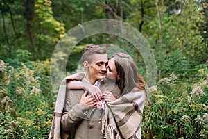 Couple under the plaid in an autumn romantic forest. Autumn wedding outdoors.