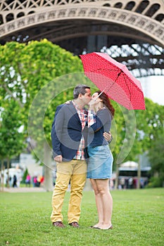 Couple under umbrella near the Eiffel tower