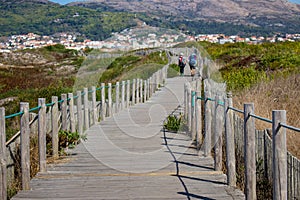 Couple of unknown pilgrims from the back walking on wooden path. Camino de Santiago way concept. Walking pilgrims with backpacks. photo