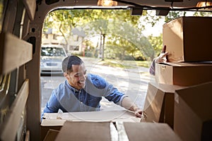 Couple Unloading Boxes From Van On Family Moving In Day