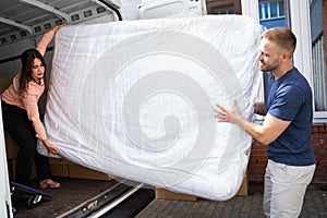 Couple Unloading Mattress From Van Or Truck