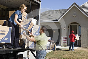 Couple Unloading Moving Boxes Into New House