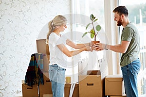 Couple unpack boxes in new home. Woman giving flower to her husband