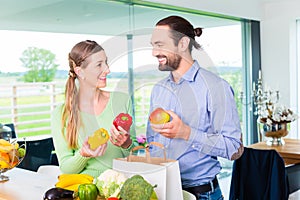 Couple unpacking grocery shopping bag at home