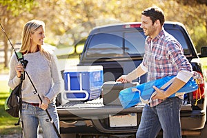 Couple Unpacking Pick Up Truck On Camping Holiday