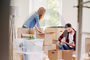 Couple unpacking stuff from carton boxes while moving-into new home