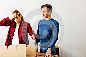 Couple unpaking boxes, woman looking to inside and aghast holding her head