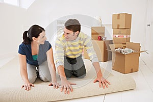 Couple Unrolling Carpet In New Home photo