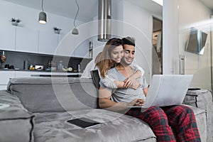 Couple Use Laptop Computer Together In Living Room, Happy Smiling Woman Embracing Man Sitting On Couch, Young People