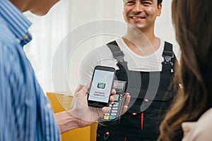 Couple uses smartphone QR code to pay post-move. Worker holds a box