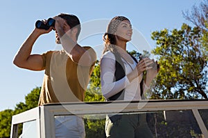 Couple using binoculars in off road vehicle