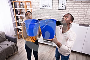 Couple Using Bucket For Collecting Water Leakage