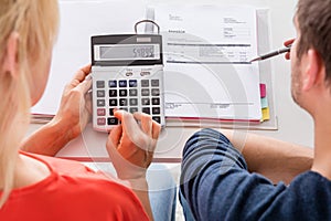 Couple Using Calculator For Calculating Invoice